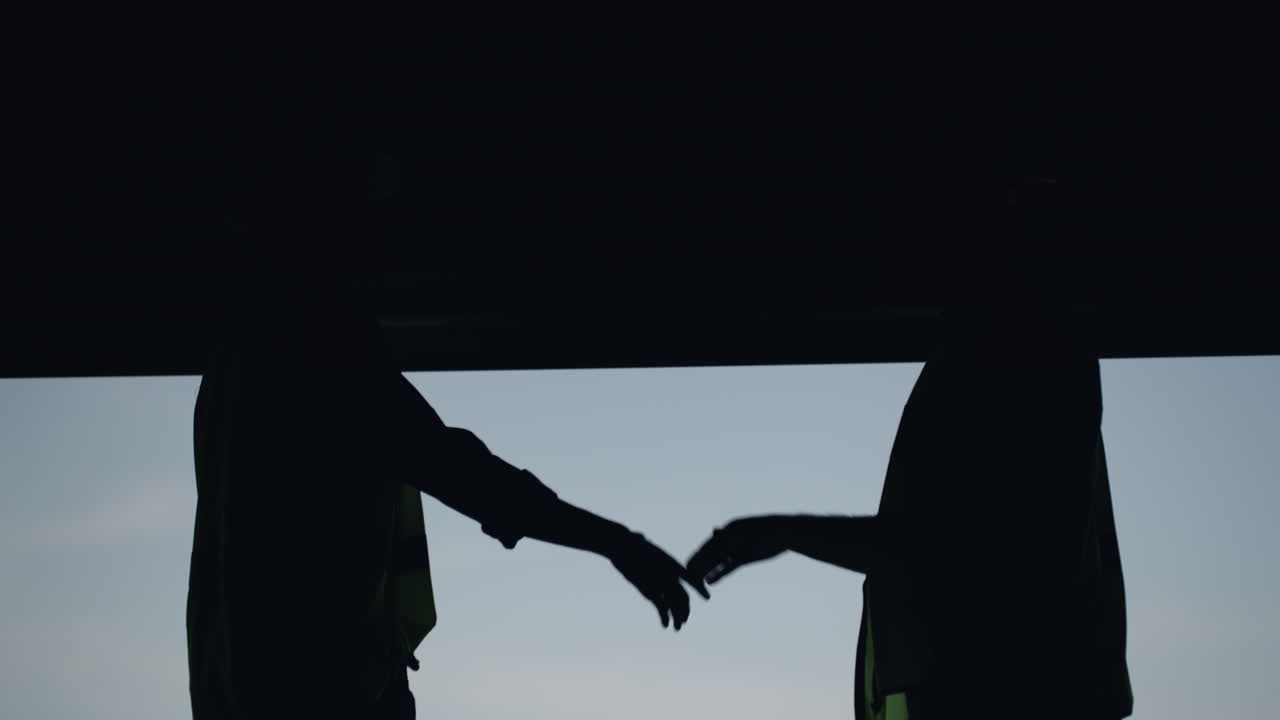 두 명의 알아볼 수 없는 사람들이 손을 흔들고 있습니다.