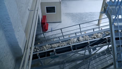 conveyor belt with rocks of kaolin moving up into machine. metal constructions and stairs at the modern industrial plant.