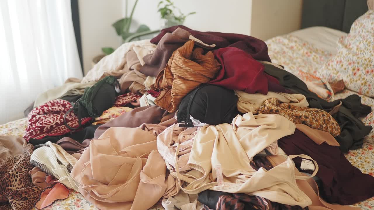Large Pile of Clothes on a Messy Bed in a Bedroom