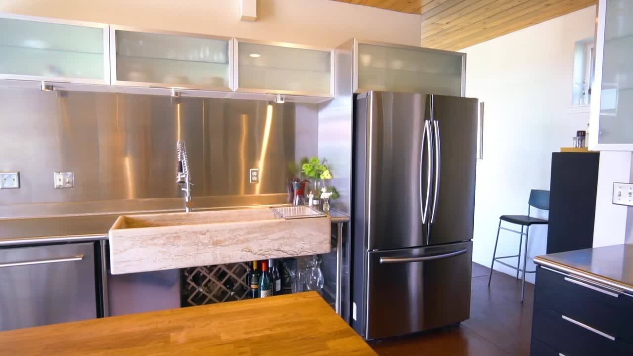 Multiple shots of a modern kitchen with stainless steel island and counter tops.