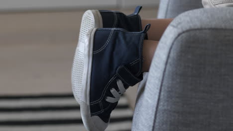 Toddler-feet-in-casual-child-shoes-while-climbing-on-couch