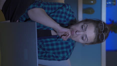 video vertical de una mujer mirando la computadora portátil con sorpresa por la noche en casa.