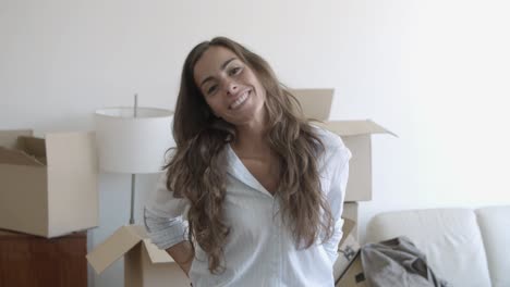 happy long-haired hair woman standing in the living room of her new house and posing for the camera