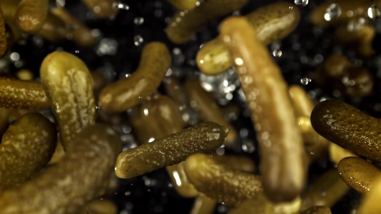 Super ralenti de cornichons marinés tombant dans l'eau