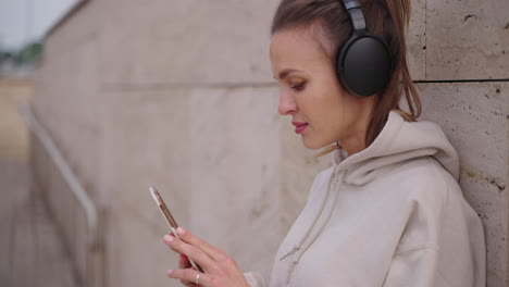 woman with headphones using a phone outdoors