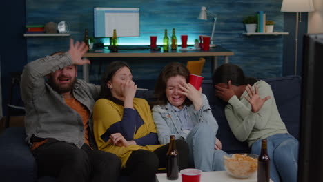 group of multiracial people sitting comfortable on couch while watching thriller movie