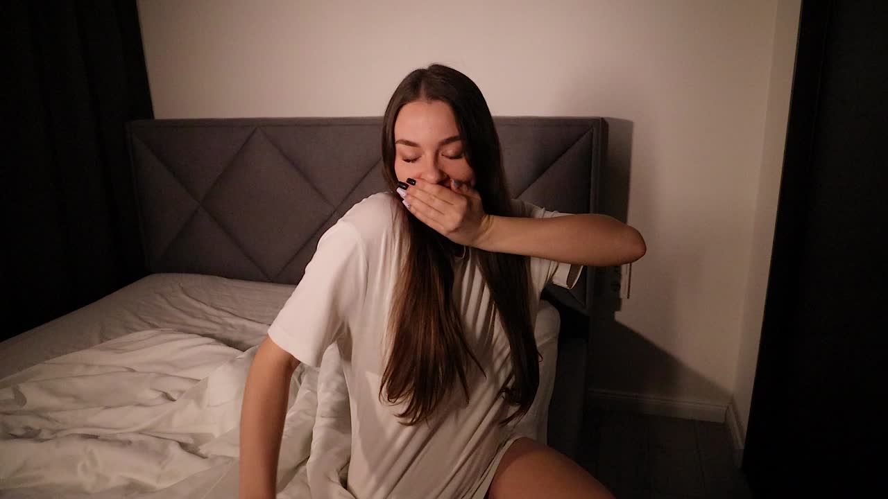 젊은 매력적인 백인 여성 모델이 잠자리에 자기 위해 준비하고 밤 휴식을 취하고 잠자는 마스크를 착용합니다.