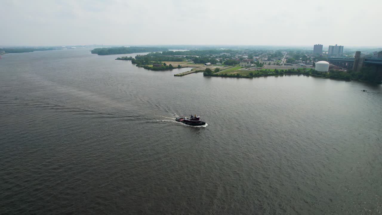 descending drone shot of a tug boat on Delaware river summer morning