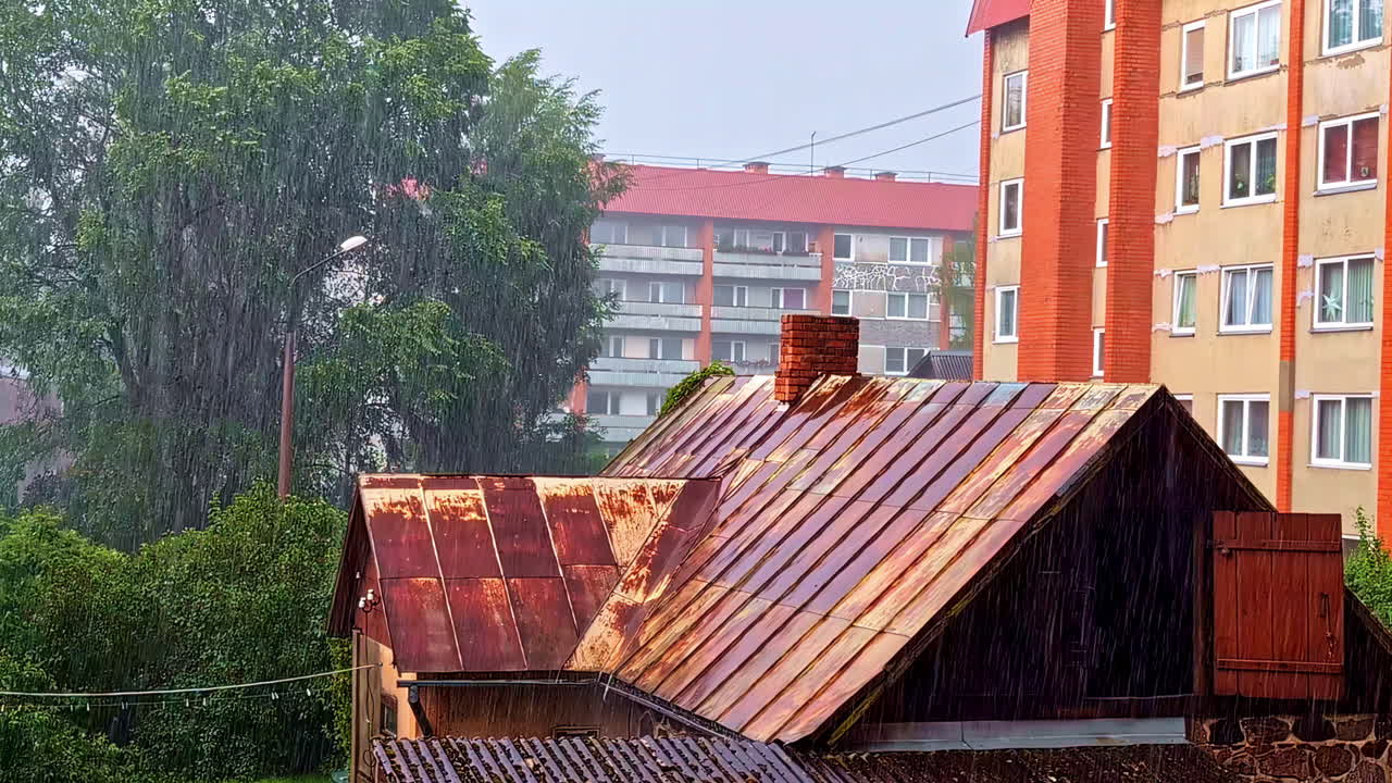 Heavy summer rain falling on houses and apartment buildings in residential area