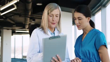 Close-up-view-of-senior-Caucasian-female-doctor-talking-with-nurse-prescribing-treatment-for-a-patient