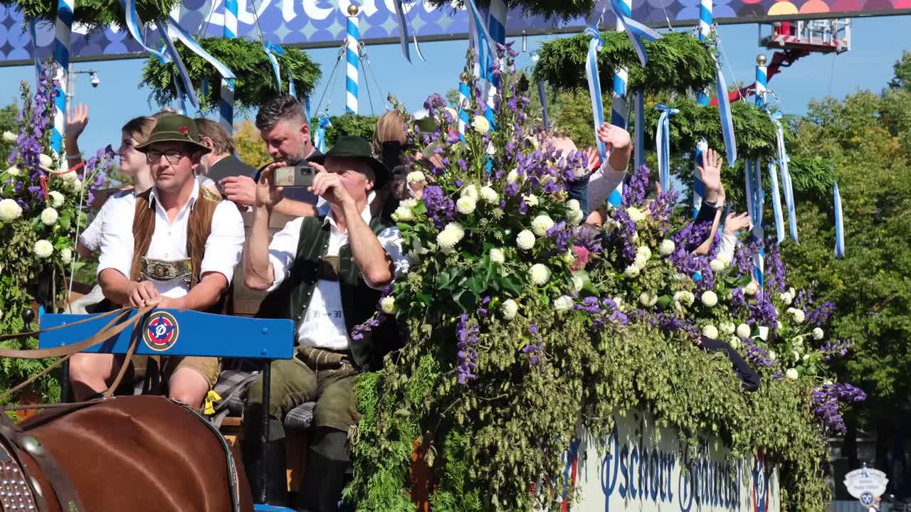 Elegantly decorated horses and a vibrant carriage adorned for Oktoberfest enter from the main street, captivating onlookers as they join the lively celebration.
