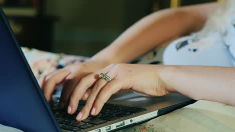 manos de mujer con anillo de diamantes en el dedo escribiendo en el teclado de la computadora portátil