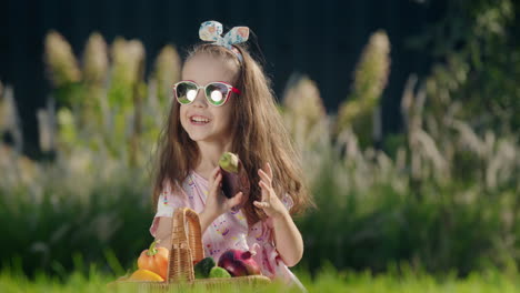 A-cute-child-is-sitting-on-the-lawn-near-a-basket-of-vegetables.-Picnic-concept