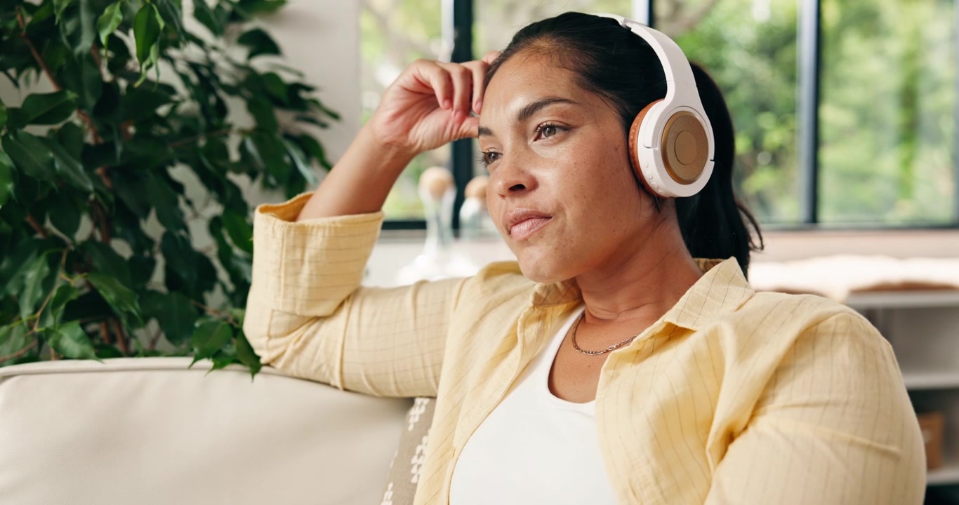 Woman Relaxing on Sofa While Listening to Music with Headphones