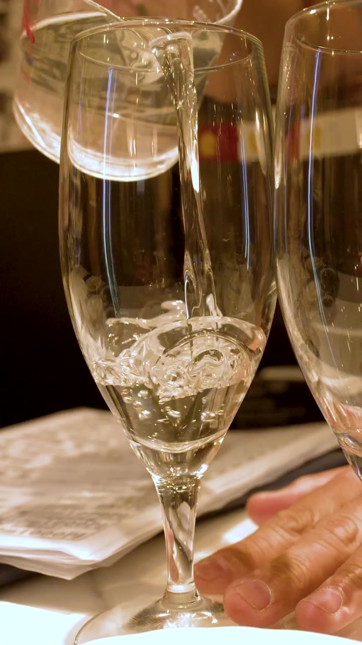 Versare vino bianco in eleganti calici in un ristorante