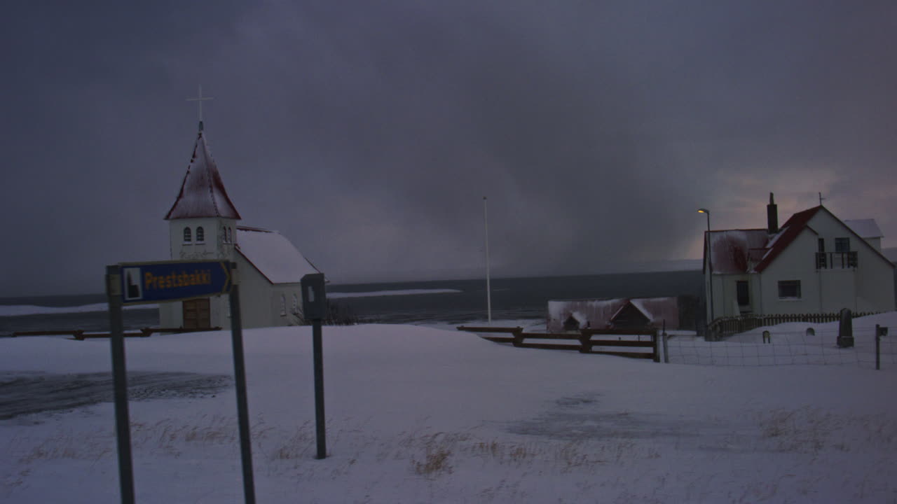 Traditional Icelandic church surrounded by snow, under dramatic Arctic skies grey with storm near ocean
