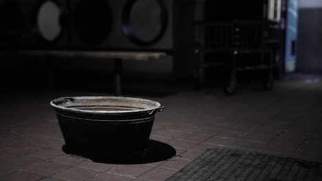 a black metal bucket in a laundry mat at night