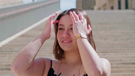 turista de cabello moreno que se quita las gafas de sol y se arregla el cabello en un día soleado en escaleras al aire libre en valletta, malta