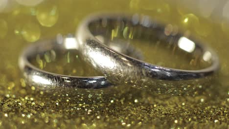 Wedding-silver-rings-lying-on-shiny-glossy-surface.-Shining-with-light.-Close-up