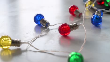 Christmas LED lights with bulbs in festive colors—blue, red, yellow, and green—are seen on a white surface
