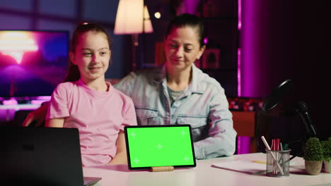 happy child and her loving mom recording green screen laptop review on online platforms