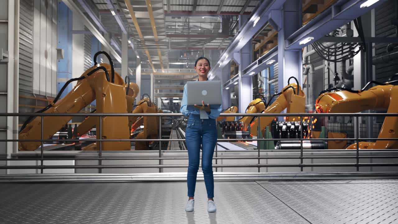 Full Body Of Asian Female With Her Laptop With Industrial Robotic Arms Working, She Observes By Looking Around Before She Come To Concentrating With Her Laptop