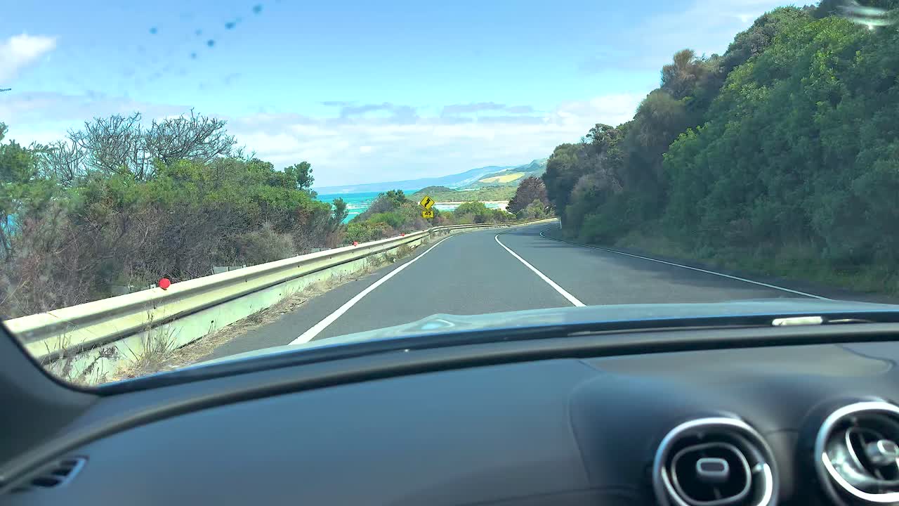 A scenic drive along Great Ocean Road with ocean views and winding roads under clear skies