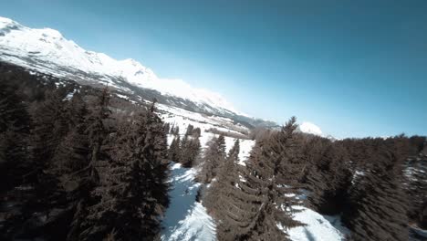 Cinemática-Fpv-Rodada-A-Lo-Largo-De-Una-Montaña-Nevada-Y-Luego-Descendiendo-Entre-árboles