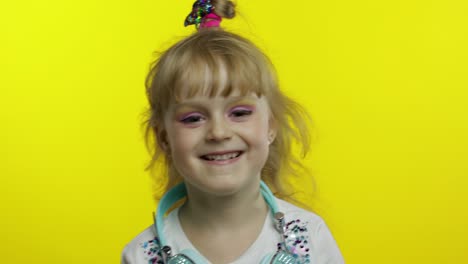 Child-smiling,-looking-at-camera.-Girl-with-headphones-on-the-neck-posing-on-yellow-background