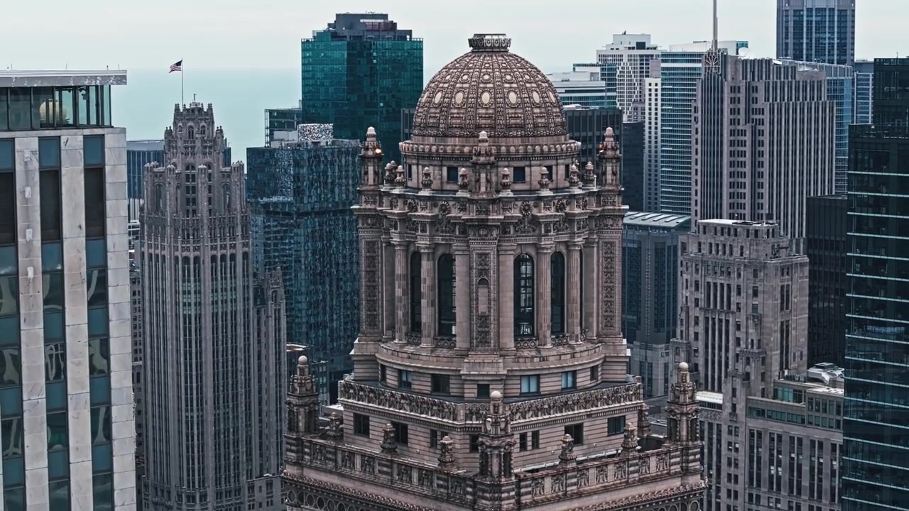 Orbita ascendente aerea con teleobiettivo della Torre gotica di Chicago, incorniciata da moderni grattacieli e vivaci strade cittadine