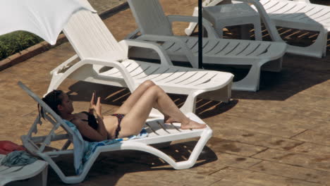 beautiful young women relaxing on the deck chair near the pool