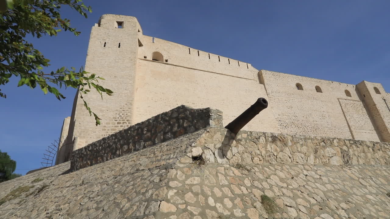 antiguo castillo tunecino con muros de piedra y cañones bajo un cielo azul claro