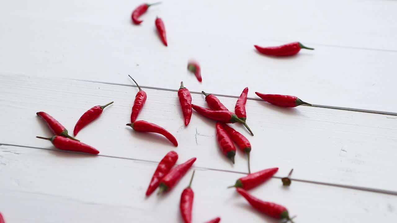 흰색 나무 테이블 슬로우 모션 비디오에 자유롭게 떨어지는 작은 빨간 고추 고추