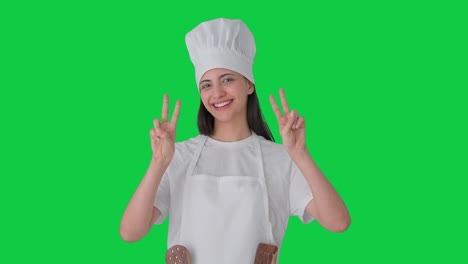 una mujer india feliz chef profesional mostrando el signo de la victoria pantalla verde