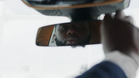 Man-adjusting-rear-view-mirror-at-car