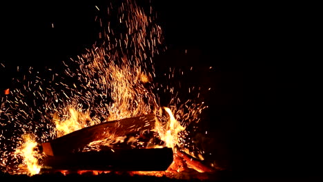 Crackling bonfire as wood is added, flickering flames and embers