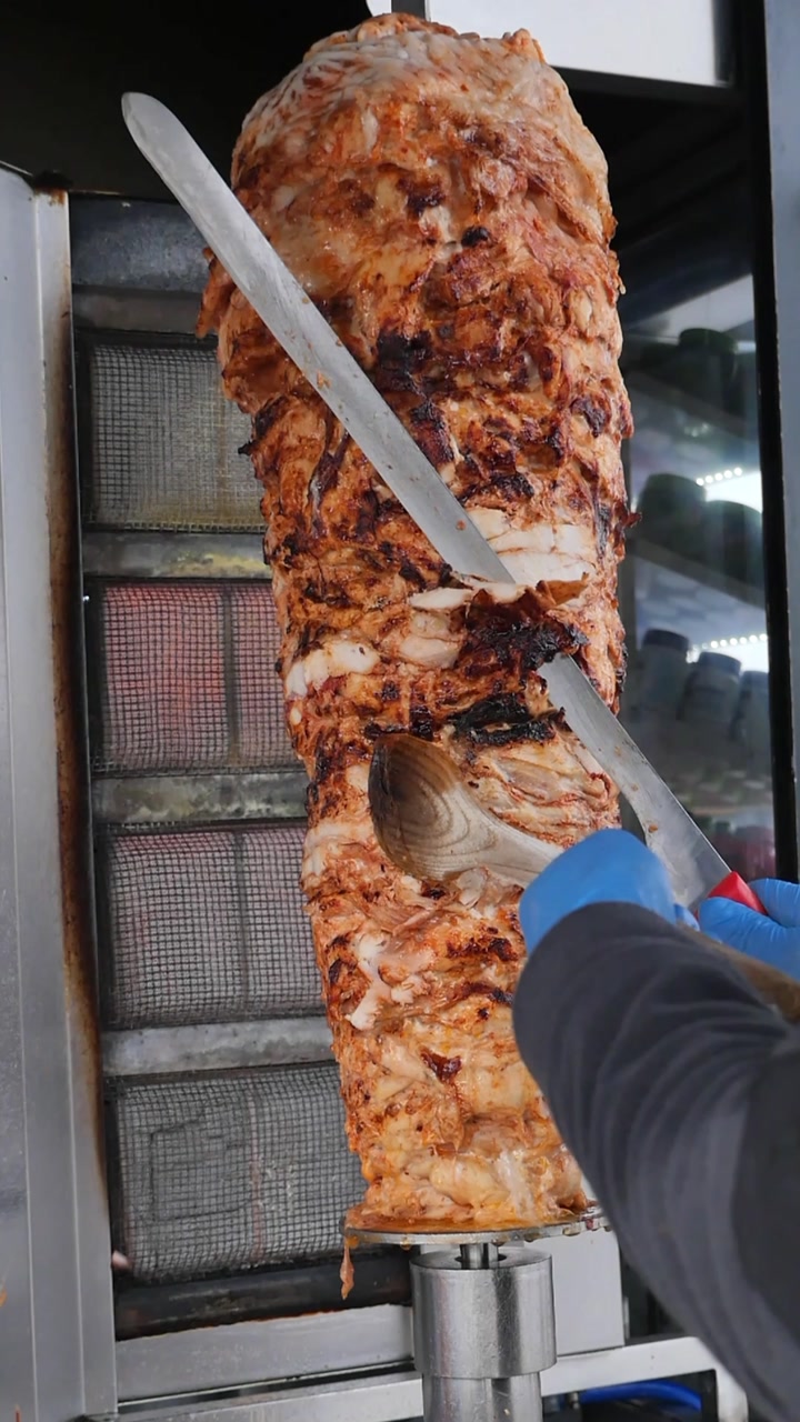 Chef affetta deliziosa carne di Doner Kebab dal girarrosto verticale