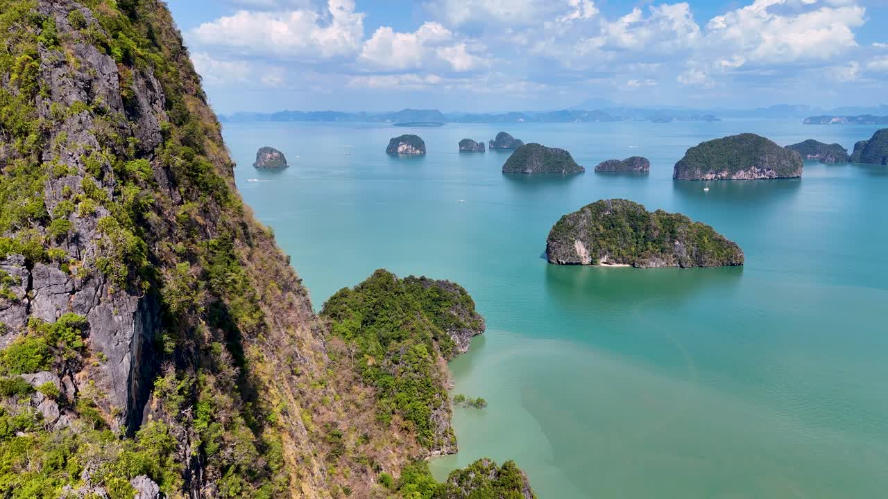 Drone footage showcasing lush islands and turquoise waters in Phang Nga Bay, Thailand, under bright daylight with clear skies