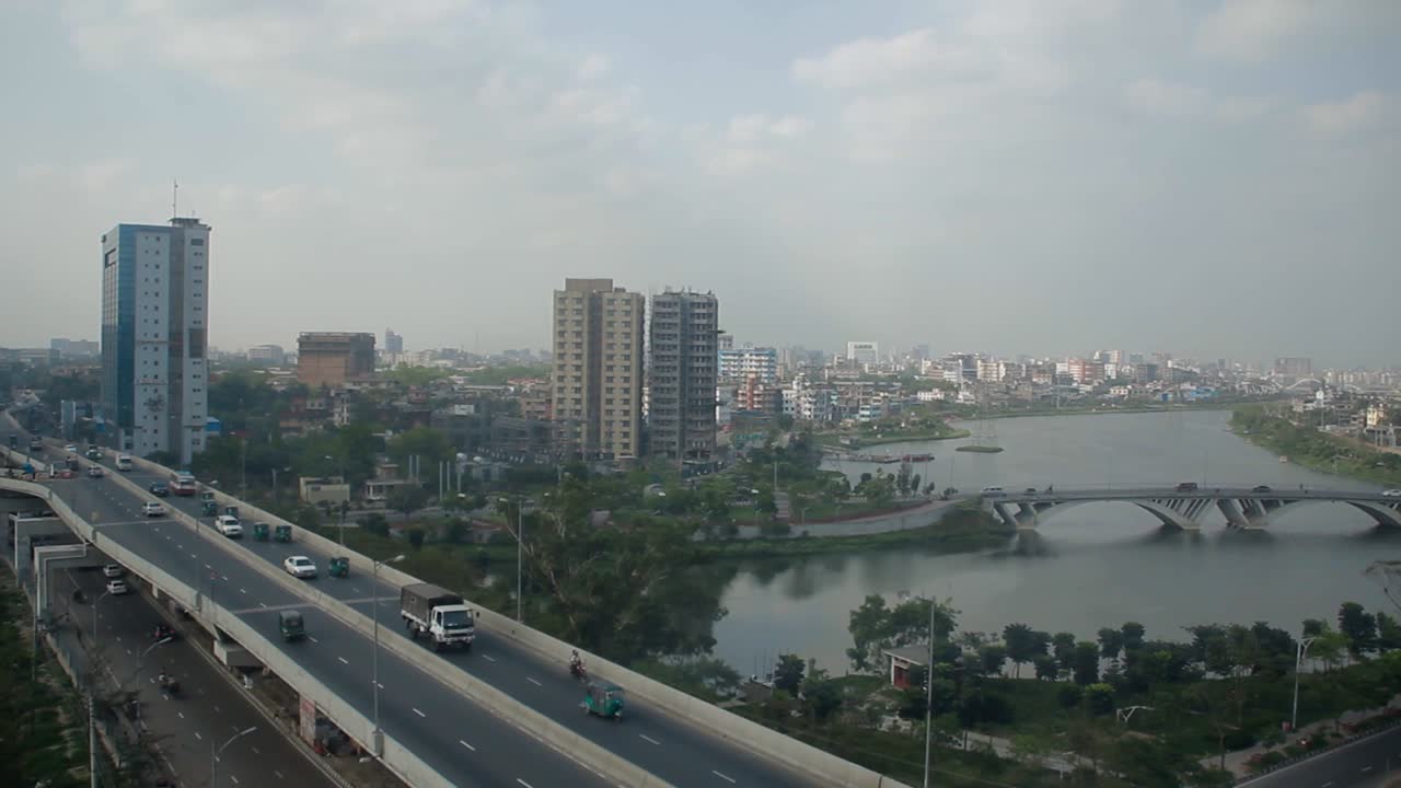 Pemandangan indah kota Dhaka dari atas, bidikan pan dari kanan ke kiri, langit luas dengan jembatan kota, danau, gedung, dan transportasi mobil