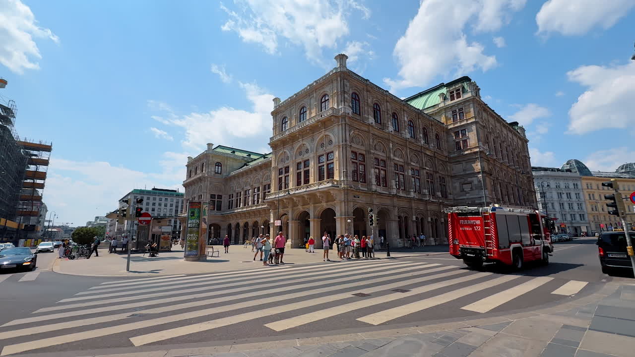 Vienna, Austria - June 9, 2025: Summer in historic Vienna. Visitors stroll near a grand building in Vienna, Austria, with a fire truck passing by on a sunny afternoon