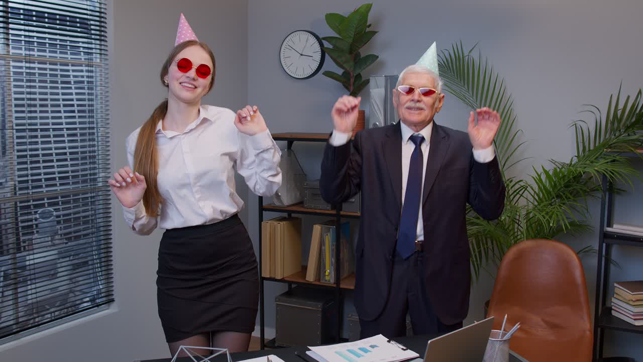 secretaria sonriente con apuesto hombre de negocios senior director de la compañía bailando baile de la victoria en la oficina