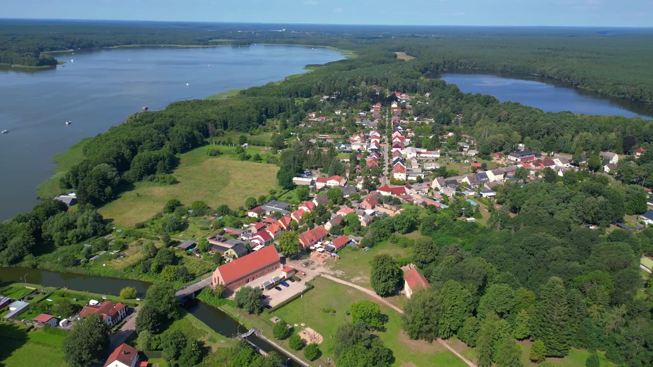 Piccolo villaggio di Himmelpfort nel Brandeburgo, Germania, circondato da laghi e foreste in una soleggiata giornata estiva. Splendida vista aerea con drone in ampia orbita panoramica