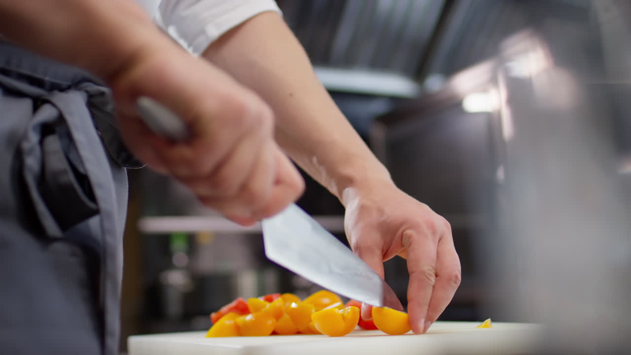 Hands of Chef Cutting Yellow Tomato