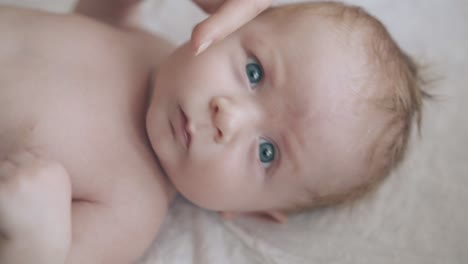 newborn with bright blue eyes short hair looks at camera