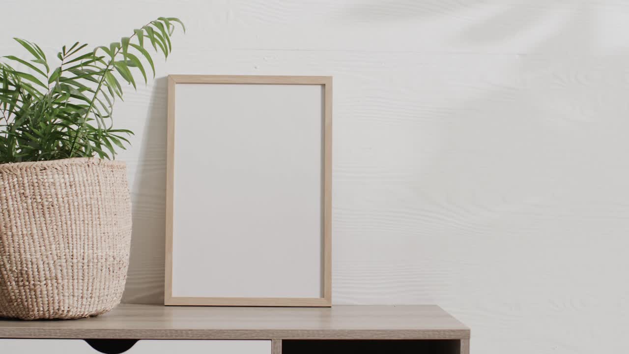 marco de madera con espacio de copia en fondo blanco con planta en el escritorio contra la pared blanca