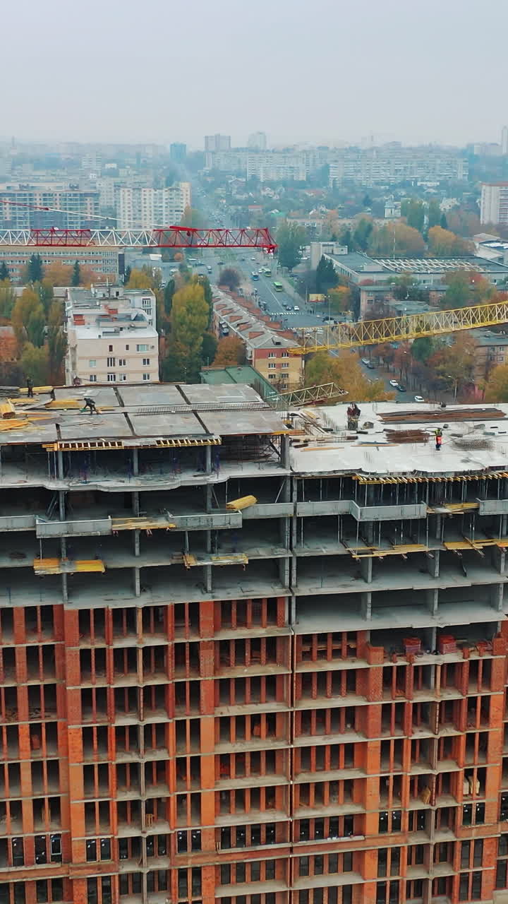 Construction site of modern multi-storey building in the city. Aerial panoramic view on a construction of a new building. Vertical video