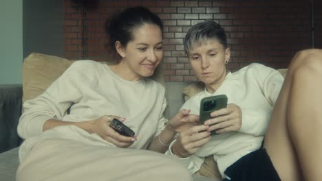 two women relaxing at home and using smartphones