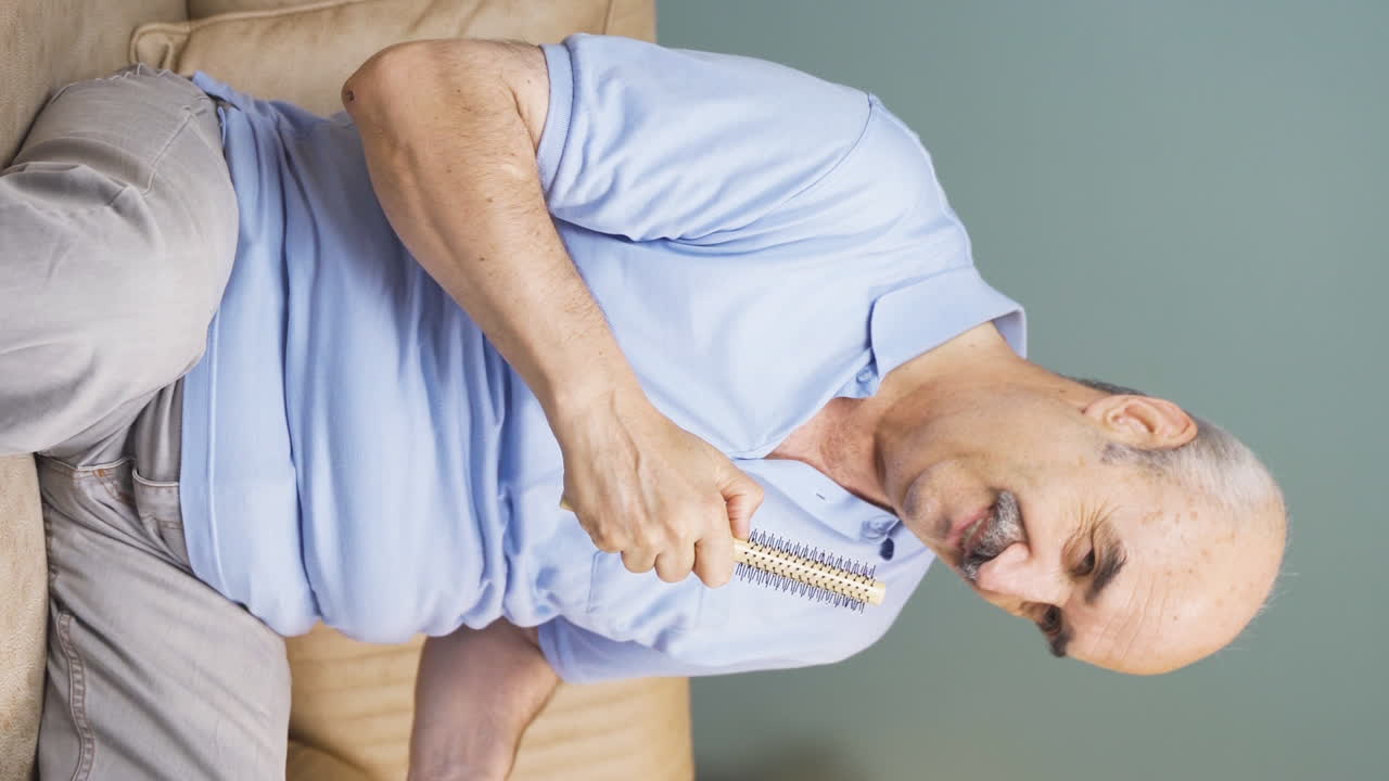 Vertical video of The old man sings to himself at home, he is relaxed and happy.