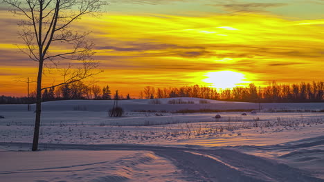 clouds float past an orange sunrise over a wintry landscape