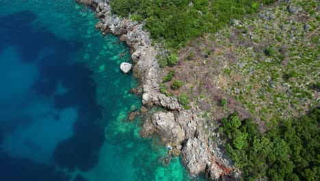 Costa-Rocosa-Vista-Desde-Arriba,-Aguas-Turquesas-Bañando-Acantilados-Y-Exuberante-Vegetación-En-La-Costa-Jónica